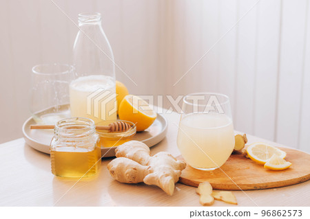Glass with drink from fresh ginger root, ingredients for its preparation honey lemon kitchen table 96862573
