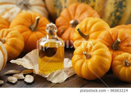Healthy pumpkin seeds oil bottle, pumpkins on wooden kitchen table. Healthy pumpkin seeds oil bottle, pumpkins on wooden kitchen table. 96863224