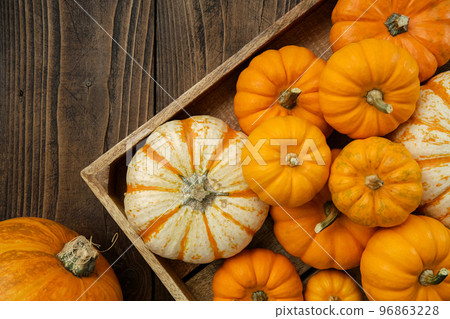 Several small pumpkins in a wooden crate on a kitchen table. Several small pumpkins in a wooden crate on a kitchen table. 96863228