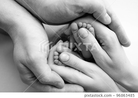 Legs, toes, feet and heels of a newborn With the hands of parents, father mother Legs, toes, feet and heels of a newborn With the hands of parents, father mother 96863485