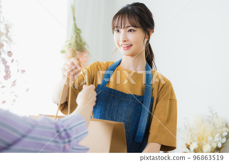 A woman in an apron serving customers A woman in an apron serving customers 96863519