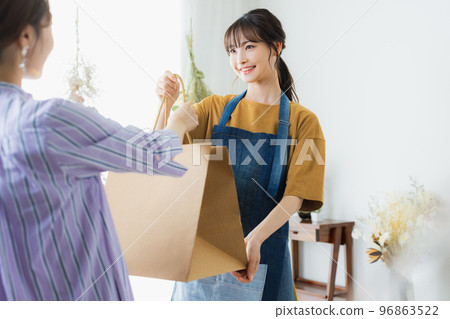 A woman in an apron serving customers A woman in an apron serving customers 96863522
