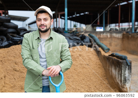 Farmer standing at farm outdoors near pile of beer bagasse 96863592