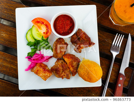 Portion of pork shashlik with vegetables and ketchup Portion of pork shashlik with vegetables and ketchup 96863773
