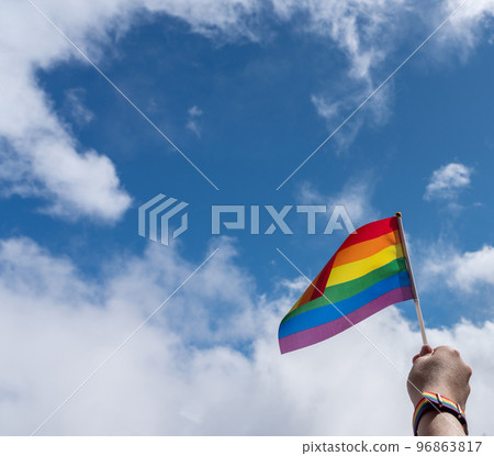 Panorama with female hand and LGBT flag against the sky 96863817