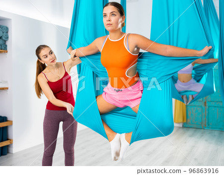 Young women making antigravity yoga exercises with group of people Young women making antigravity yoga exercises with group of people 96863916