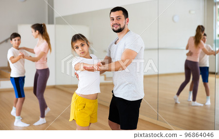 Young girl dancing waltz with her dad in gym Young girl dancing waltz with her dad in gym 96864046