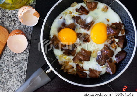 Eggs with mushrooms frying in pan in kitchen 96864142