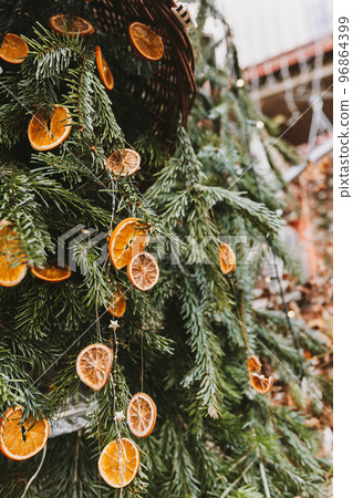 Natural decoration made of dry orange slices on pine branch. Diy Christmas food decoration. Environment, recycle, reuse and zero waste concept. Selective focus 96864399