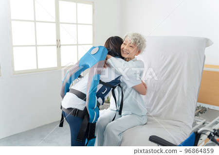 穿著動力輔助服並協助老年人的護理人員 96864859