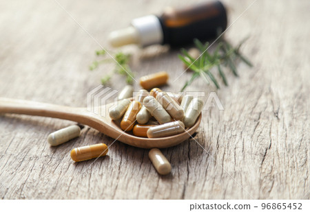 Herbal capsules from herbal oil with wooden spoon and copy space for using in medical background, healthy eating for good life 96865452