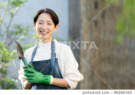 Image of a woman whose hobby is gardening or a shop clerk holding a shovel looking at the camera 96866560