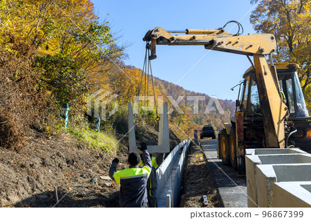 Installation of concrete drains precast in u-shapes on reconstruction road as means of draining surface 96867399
