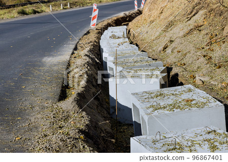 Installing precast u-shape concrete drains along reconstruction road for purpose of draining ground 96867401