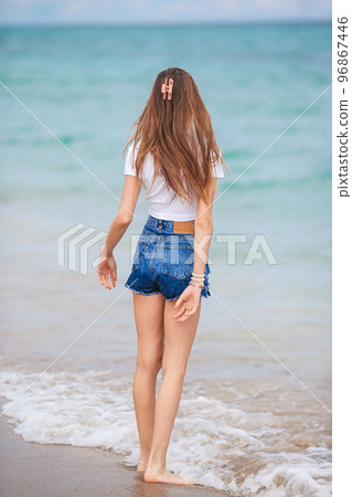 Little happy girl splashing and running in clear turquoise water 96867446