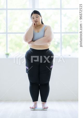 A woman thinking on a weight scale 96872515