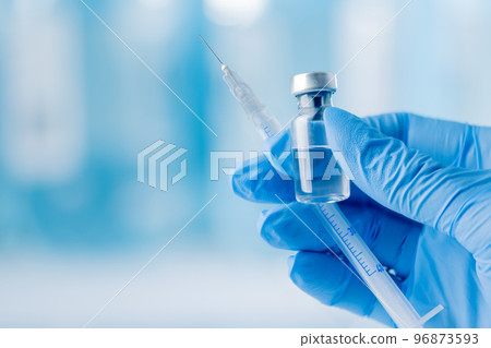 Doctor's hand holding glass vial and syringe with injection over blue background. Vaccination or beauty therapy concept. Doctor's hand holding glass vial and syringe with injection over blue background. Vaccination or beauty therapy concept. 96873593