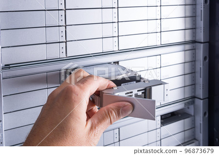 network administrator is installing new hard disk into data storage array inside internet cloud center 96873679