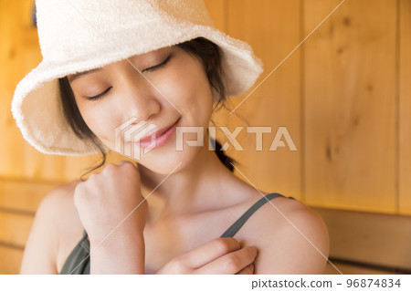 A young woman wearing a sauna hat and entering a sauna 96874834