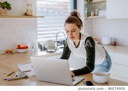 Young woman having homeoffice in her kitchen. 96874989
