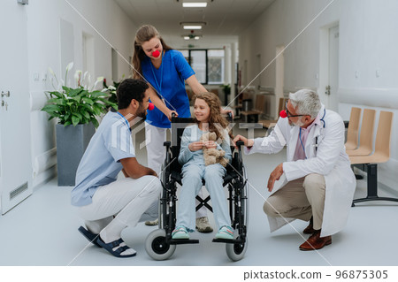 Happy doctors with clown red noses taking care about little girl. Happy doctors with clown red noses taking care about little girl. 96875305