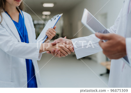 Close-up of doctors shaking hands at hospital corridor. Close-up of doctors shaking hands at hospital corridor. 96875309