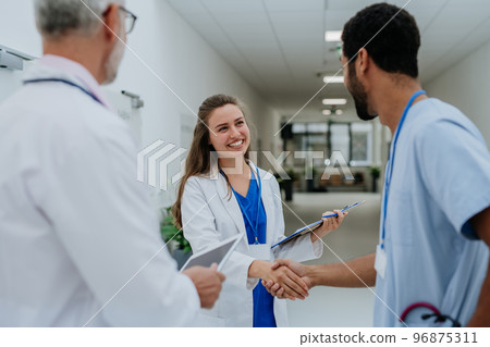 Doctors greetings and shaking hands at hospital corridor. 96875311