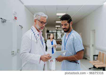 Doctors discussing something at hospital corridor. Doctors discussing something at hospital corridor. 96875316