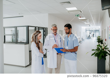 Doctors discussing something at hospital corridor. Doctors discussing something at hospital corridor. 96875320