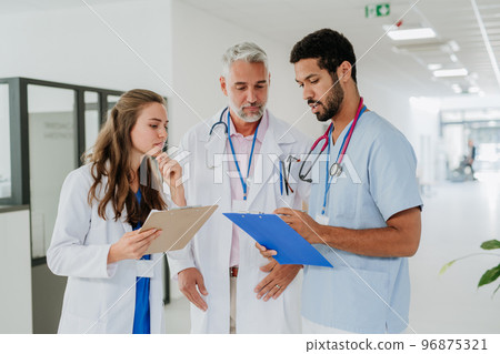 Team of doctors discussing something at hospital corridor. Team of doctors discussing something at hospital corridor. 96875321