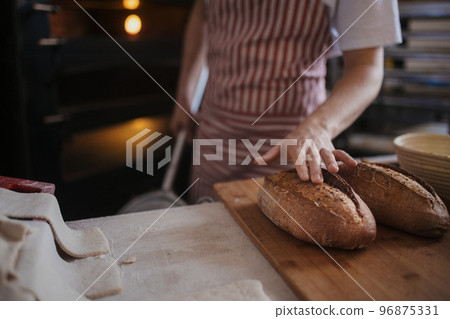 Close-up of baker with fresh bread. Close-up of baker with fresh bread. 96875331