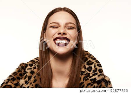 Portrait of beautiful woman posing in animal print coat over white background. Smiling. White teeth. Piercing. Autumn make-up look Portrait of beautiful woman posing in animal print coat over white background. Smiling. White teeth. Piercing. Autumn make-up look 96877753