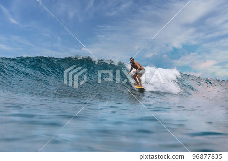 Shirtless male surfer on a wave at sunny day Shirtless male surfer on a wave at sunny day 96877835