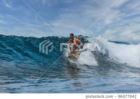 Shirtless male surfer on a wave at sunny day Shirtless male surfer on a wave at sunny day 96877842