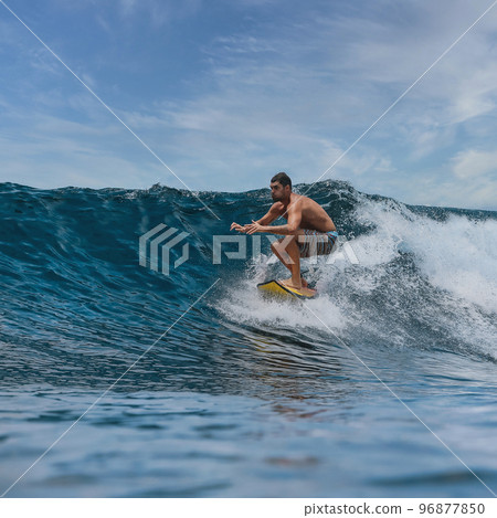 Shirtless male surfer on a wave at sunny day Shirtless male surfer on a wave at sunny day 96877850