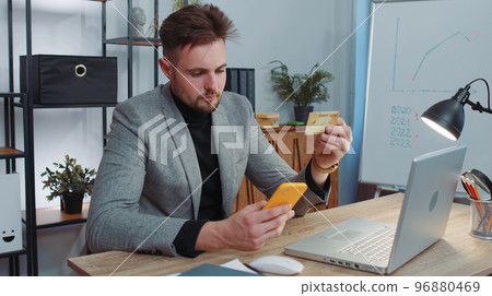 Business man making online purchase payment shopping with credit bank card and smartphone at office Business man making online purchase payment shopping with credit bank card and smartphone at office 96880469