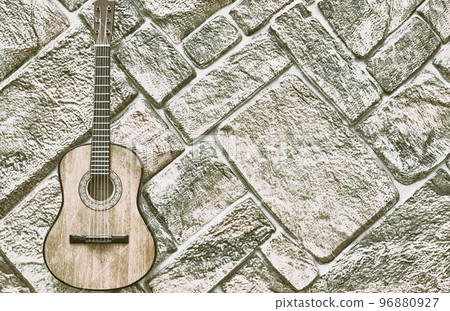 Gray silver acoustic guitar on gray brick wall 96880927