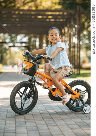 Happy little girl riding a bike and looking excited 96881099