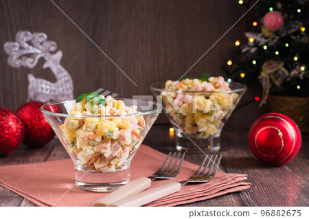 Russian olivier salad of sausage and boiled vegetables in bowls on a wooden table Russian olivier salad of sausage and boiled vegetables in bowls on a wooden table 96882675