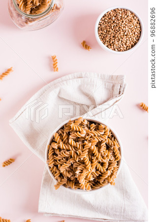 Bowls with raw buckwheat pasta and groats on the table. Alternative to wheat. Top and vertical view Bowls with raw buckwheat pasta and groats on the table. Alternative to wheat. Top and vertical view 96882696