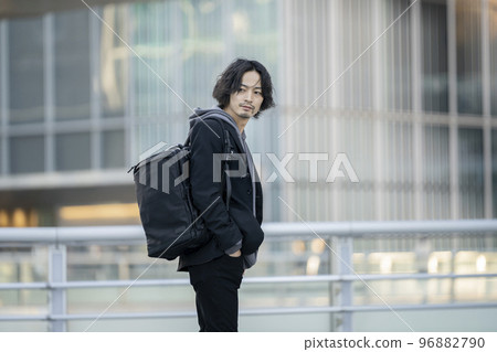 一個 30 歲出頭的男人背著背包全身看著相機 96882790