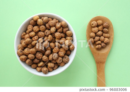 Chufa, tigernut, earth almond on white ceramic bowl and wooden spoon on green background. Healthy vegan food concept. Tiger nut for flour, oil, milk, traditional typical drink horchata Valencia Spain Chufa, tigernut, earth almond on white ceramic bowl and wooden spoon on green background. Healthy vegan food concept. Tiger nut for flour, oil, milk, traditional typical drink horchata Valencia Spain 96883006