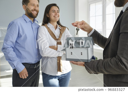 Real estate agent hands over the key to a new house to a happy young family couple Real estate agent hands over the key to a new house to a happy young family couple 96883327