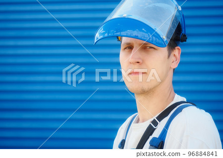 Portrait of young worker in protective helmet on blue industrial background with space for copying Portrait of young worker in protective helmet on blue industrial background with space for copying 96884841