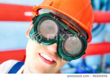 Head of worker in construction helmet and protective glasses close-up. Crazy weirdo wriggles at Head of worker in construction helmet and protective glasses close-up. Crazy weirdo wriggles at 96884848