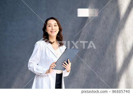 一位穿著實驗室外套的微笑女醫生在醫院檢查病歷 96885740