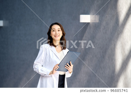 A smiling female doctor in a lab coat checking a medical record at the hospital 96885741