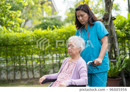 Doctor caregiver help and care Asian senior or elderly old lady woman patient sitting on wheelchair in park at nursing hospital, healthy strong medical concept 96885956