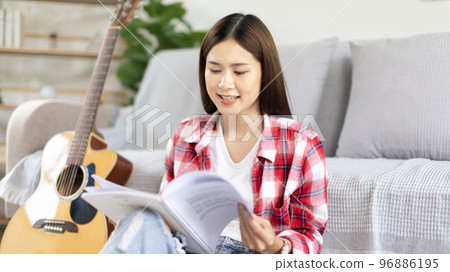 Asian woman specializes in music is composing the lyrics and melody for the opening of a new single, Using imagination and concentration in creating music, acoustic guitar, Creation of music notes. Asian woman specializes in music is composing the lyrics and melody for the opening of a new single, Using imagination and concentration in creating music, acoustic guitar, Creation of music notes. 96886195