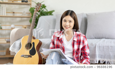 Asian woman specializes in music is composing the lyrics and melody for the opening of a new single, Using imagination and concentration in creating music, acoustic guitar, Creation of music notes. Asian woman specializes in music is composing the lyrics and melody for the opening of a new single, Using imagination and concentration in creating music, acoustic guitar, Creation of music notes. 96886196